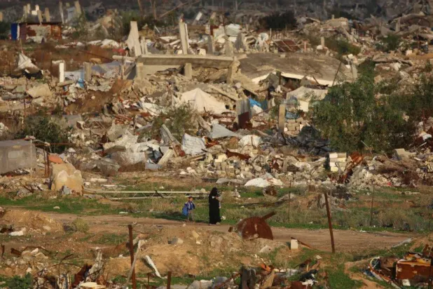 Gazze Şeridi'nin orta kesimlerindeki Nuseyrat Mülteci Kampı’nda savaşın yol açtığı yıkımın ortasında yürüyen Filistinli bir kadın (AFP)