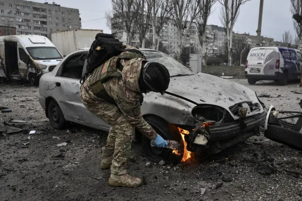 ضابط شرطة يُطفئ سيارة محترقة في موقع غارة جوية روسية بطائرة مسيَّرة وسط الهجوم على أوكرانيا في زابوروجيا (رويترز)