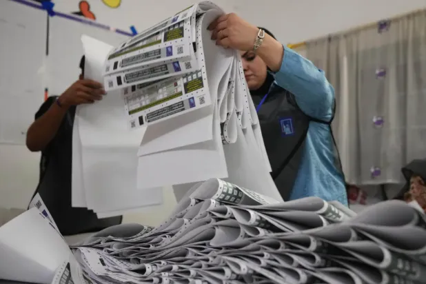 Election workers gather parliamentary election ballots after the polls closed in Baghdad, Iraq, Nov. 11, 2025. (AP Photo/Hadi Mizban, File)