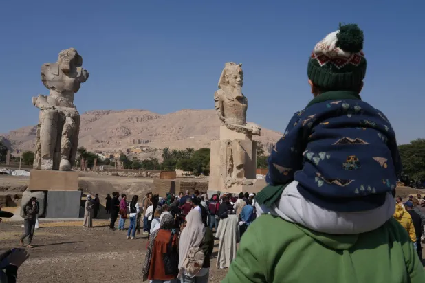 Visitors watch the two giant reassembled alabaster statues of Pharoah Amenhotep III, in the southern city of Luxor, Egypt, Sunday, Dec. 14, 2025. (AP Photo/Amr Nabil)