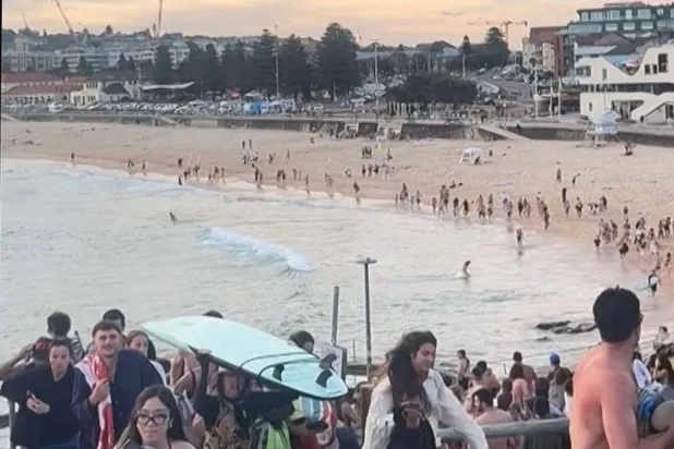 This screen grab of UGC video taken on December 14, 2025 and received courtesy of Mike Ortiz shows beach-goers fleeing Bondi Beach after gunmen opened fire, in Sydney on December 14, 2025. (Photo by Mike Ortiz / UGC / AFP) 