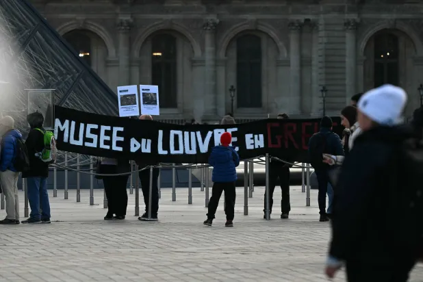 This photograph shows a banner which reads "Louvre Museum on Strike" outside the entrance to the Louvre as museum workers voted to go on strike against increasingly deteriorating working conditions and the declining visitor experience at the world famous museum, in Paris on December 15, 2025. (AFP)