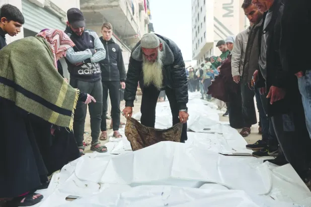 Gazze şehrinin er-Rimal mahallesinde 2023 yılında yıkılan bir binanın enkazından çıkarılan cesetlerin kimliklerini tespit etmeye çalışan Filistinliler (AFP)