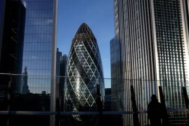 شخص ينظر من حديقة على سطح مبنى في منطقة الأعمال بمدينة لندن (رويترز)