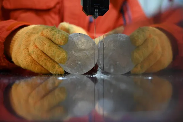 A researcher cuts a slice from an ice core sample taken from a glacier in the Pamir mountain range in Tajikistan, at the Hokkaido University Institute of Low Temperature Science, in Sapporo, in northern Japan's Hokkaido prefecture on December 9, 2025. (Photo by GREG BAKER / AFP)