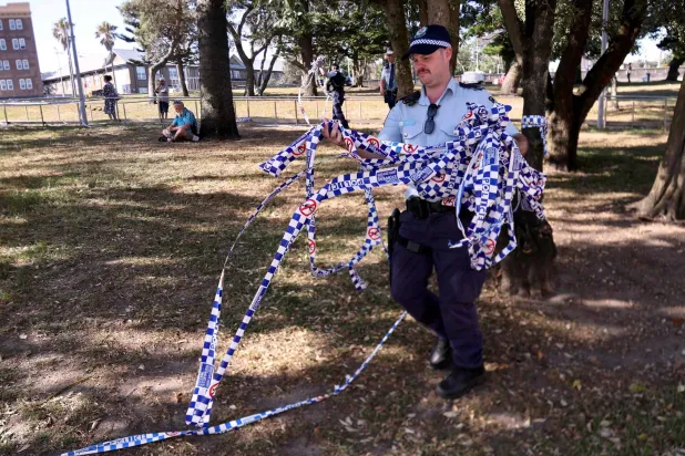 Police officers remove police tape from the scene of Sunday's shooting at Bondi Beach, in Sydney on December 17, 2025. (AFP)