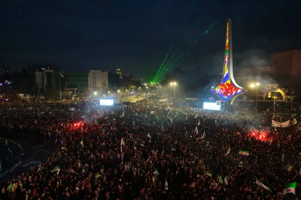 An aerial photograph shows thousands of people celebrating the first anniversary since the ousting of longtime ruler Bashar al-Assad near The Damascus Sword monument in Umayyad Square, in the Syrian capital Damascus on December 8, 2025. (AFP) 