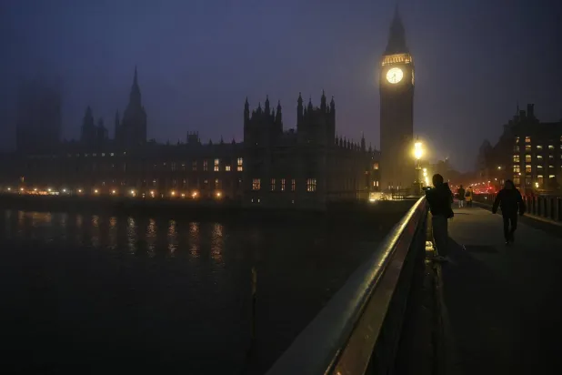 Pedestrians walk across Westminster Bridge as early morning fog covers the streets of London on December 17, 2025. (Photo by JUSTIN TALLIS / AFP)
