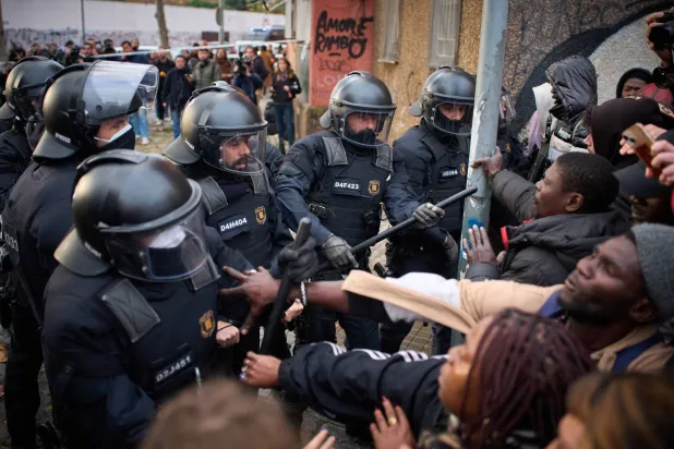 Migrants confront police as they begin carrying out eviction orders at an abandoned school building where hundreds of mostly undocumented migrants had been living, in Badalona, near Barcelona, Spain, Wednesday, Dec. 17, 2025. (AP Photo/Emilio Morenatti)