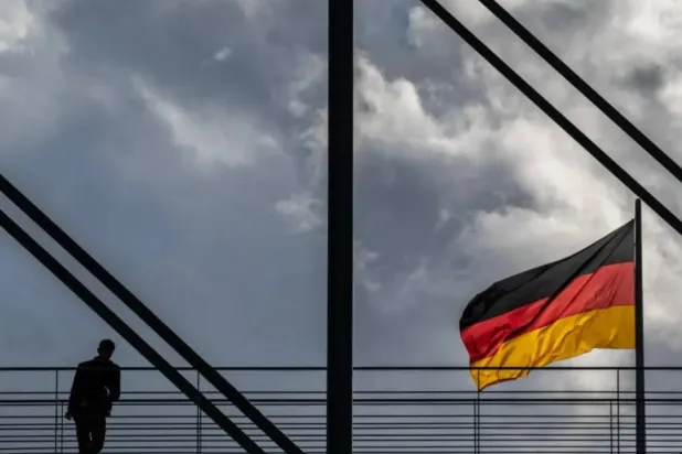 A man pauses on a pedestrian bridge as a German flag flies over the Reichstag building in Berlin on October 23, 2024. (AFP)
