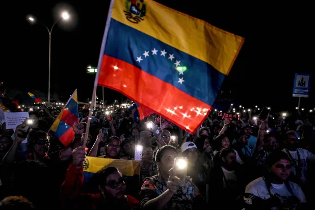 Supporters of Venezuela's President Nicolas Maduro wave a Venezuelan flag during a rally demanding peace in Caracas on December 15, 2025. (Photo by Juan BARRETO / AFP)