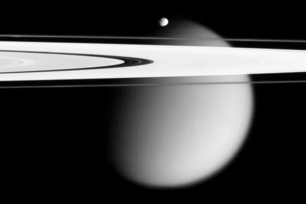 This image made by the Cassini spacecraft and provided by NASA on March 12, 2006, shows two of Saturn's moons, the small Epimetheus and smog-enshrouded Titan, with Saturn's A and F rings stretching across the frame. (NASA via AP)