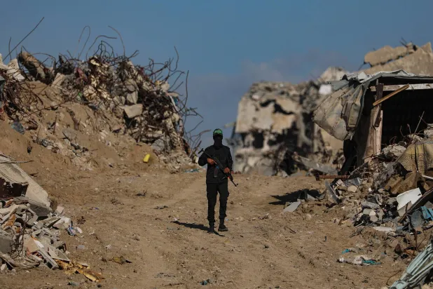 مقاتل من «كتائب القسام» التابعة لـ«حماس» يتابع البحث عن جثث رهائن إسرائيليين بمشاركة عناصر الصليب الأحمر وسط مخيم جباليا شمال غزة 1 ديسمبر 2025 (إ.ب.أ)