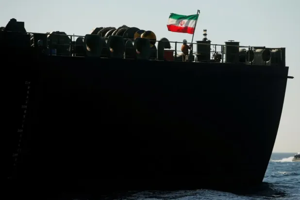 A crew member raises the Iranian flag on Iranian oil tanker Adrian Darya 1, previously named Grace 1, as it sits anchored after the Supreme Court of the British territory lifted its detention order, in the Strait of Gibraltar, Spain, August 18, 2019. REUTERS/Jon Nazca
