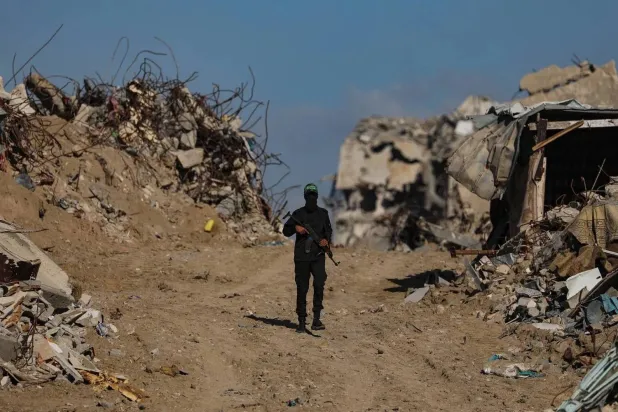 A fighter from the Izz ad-Din al-Qassam Brigades, affiliated with Hamas, oversees the search for the bodies of Israeli hostages, with the participation of Red Cross personnel, in the Jabalia refugee camp in northern Gaza, Dec. 1, 2025. (EPA) 