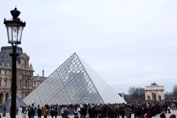 زوار يصطفون قرب الهرم الزجاجي لمتحف اللوفر للدخول (رويترز)