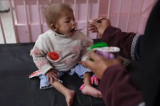 Şiddetli yetersiz beslenmeden muzdarip Gazzeli kız Acvan, dün Han Yunus'taki el-Nasır Hastanesi'nde annesinden yiyecek alıyor (Reuters)