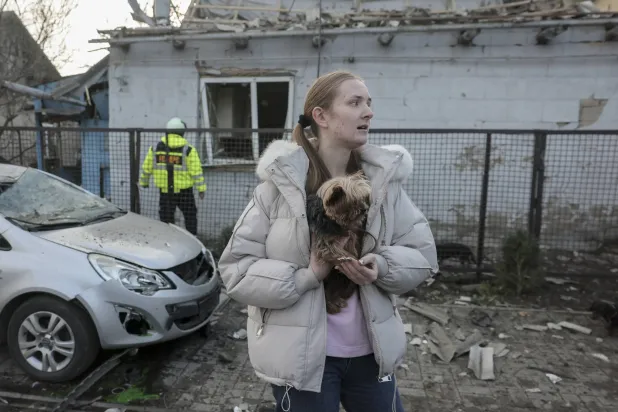 امرأة محلية برفقة كلبها تتفاعل مع موقع غارة روسية على مبنى خاص في زابوروجيا (إ.ب.أ)