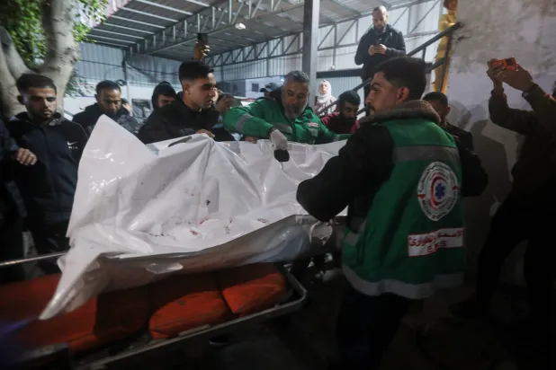 Palestinians carry the body of a person killed in an Israeli military strike as they arrive at Shifa Hospital in Gaza City, Friday, Dec. 19, 2025. (AP Photo/Yousef Al Zanoun)