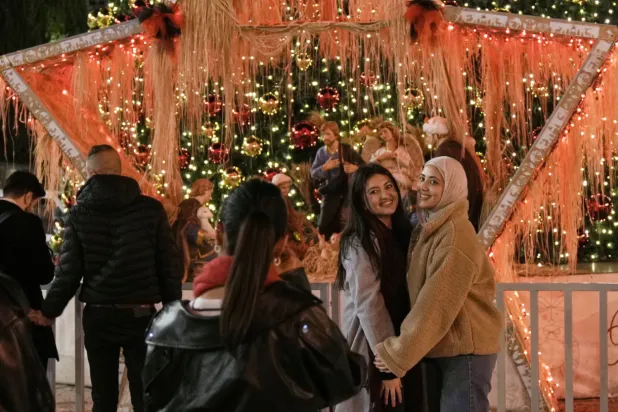 People pose for a picture in Manger Square in the West Bank city of Bethlehem, Tuesday, Dec. 16, 2025. (AP Photo/Mahmoud Illean)
