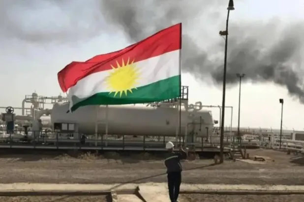 A staff at an oilfield holds the flag of Kurdistan. (X)

