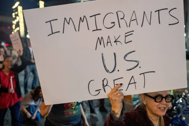 A woman holds a poster as immigrants rights activists stage a traditional Mexican posada, reenacting Mary and Joseph’s search for shelter, to symbolize immigrants seeking refuge from Immigration and Customs Enforcement (ICE) agents during the ongoing immigration operation "Catahoula Crunch", in New Orleans, Louisiana, US, December 18, 2025. REUTERS/Seth Herald