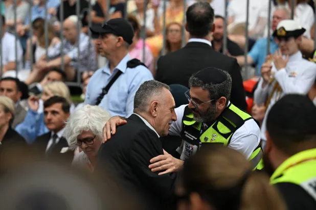 محمد فاتح الأحمد (في الوسط) والد أحمد الأحمد بطل حادثة إطلاق النار في بونداي يحضر وقفة إحياء ذكرى الضحايا والناجين من مجزرة بونداي في اليوم الوطني للتأمل على شاطئ بونداي في سيدني بأستراليا يوم 21 ديسمبر 2025 (إ.ب.أ)