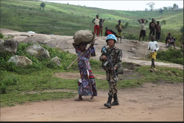 جندي من «بعثة الأمم المتحدة لتحقيق الاستقرار في الكونغو الديمقراطية» يصطحب امرأة كونغولية نازحة داخلياً (رويترز)