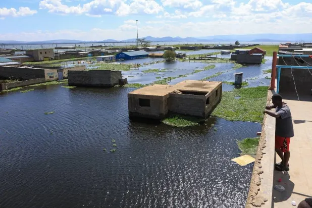 A man stands on a rooftop overlooking submerged homes after rising waters from Lake Naivasha flooded Kihoto Village, displacing hundreds, in Naivasha, Kenya's Rift Valley region, on Tuesday, Nov. 11, 2025. (AP Photo/Andrew Kasuku)