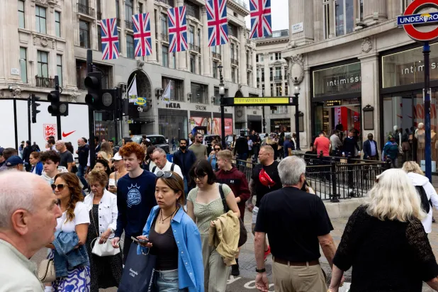 أشخاص ومتسوقون يعبرون مفترق الطرق في «أكسفورد سيرك» بلندن (رويترز)