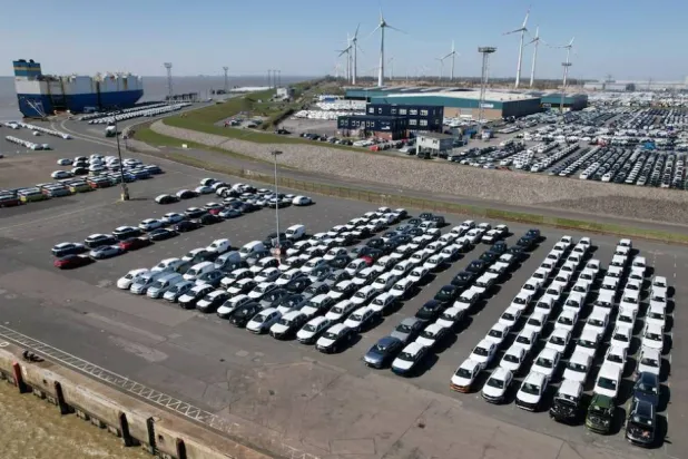 صورة جوية تُظهر سيارات مجموعة «فولكسفاغن» متجهة نحو شحنها على متن سفينة للتصدير إلى الولايات المتحدة بميناء إمدن (رويترز)
