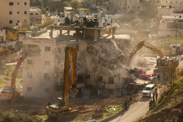 Israeli forces gather as an excavator demolishes a building built without a permit in the east Jerusalem neighborhood of Wadi Qaddum on December 22, 2025. (AFP)