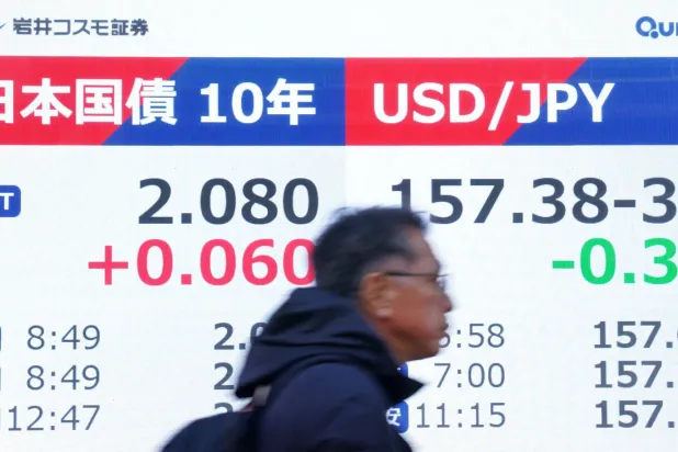 رجل يمر أمام شاشة تعرض سعر الين الياباني مقابل الدولار الأميركي وسط العاصمة طوكيو (أ.ف.ب)