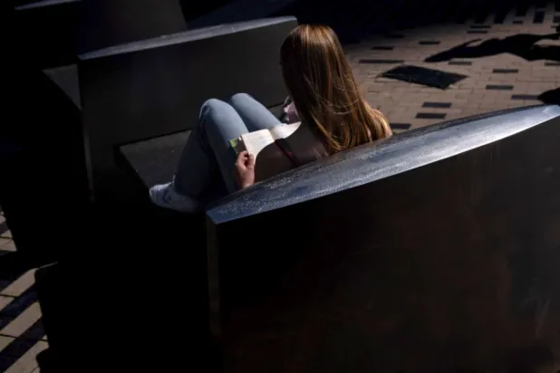 A woman reads a book in the afternoon sun on a bench outside South Station in Boston, on Friday, May 31, 2024. (AP Photo/David Goldman, File)

