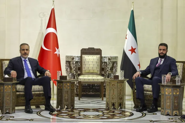 FILE: In this handout photo released by the Turkish Foreign Ministry press service, Turkish Foreign Minister Hakan Fidan, left, sits with Syria's interim president Ahmad Al-Sharaa, during their meeting in Damascus, Syria, Thursday, March 13, 2025. (Turkish Foreign Ministry press service via AP)
