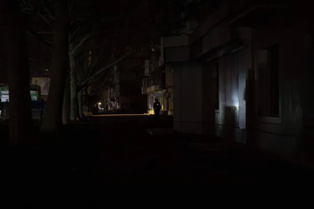 A person walks on a non-illuminated street during during a power outage in the southern city of Odesa, on December 22, 2025, following Russian missile and drone attacks on Ukrainian energy infrastructures. (Photo by Oleksandr GIMANOV / AFP)