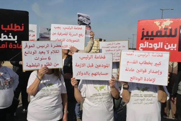 Depositors hold protest banners against the draft deposit recovery law during popular demonstrations on the road to the Presidential Palace (Asharq Al-Awsat). 