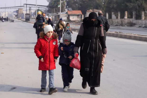 Şam ve SDG'nin pazartesi akşamı gerilimi azaltma konusunda anlaşmasının ardından Suriye, Halep'te iki çocuğuyla birlikte yürüyen bir kadın (Reuters)