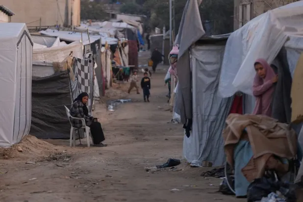 A woman sits next to her tent on an alley of a makeshift tent camp for displaced Palestinians in Deir al-Balah, central Gaza Strip, Tuesday, Dec. 23, 2025. (AP)