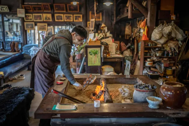 This picture taken on December 12, 2025 shows a member of staff grilling fish over a hearth at a restaurant which offers bear meat in Chichibu, Saitama prefecture. (AFP)