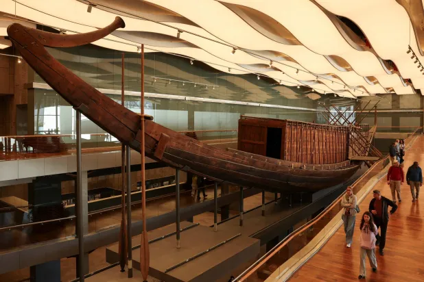 People walk next to King Khufu's boat gem, also known as the Solar Boat, as work to restore the second solar boat has started with wooden planks part of the 1,650-piece structure being installed on a metal frame through Egyptian-Japanese cooperation with two Japanese universities, marking the start of preparations for the second boat's public display at the Grand Egyptian Museum (GEM), near the Giza Pyramid Complex, in Giza, Egypt, December 23, 2025.