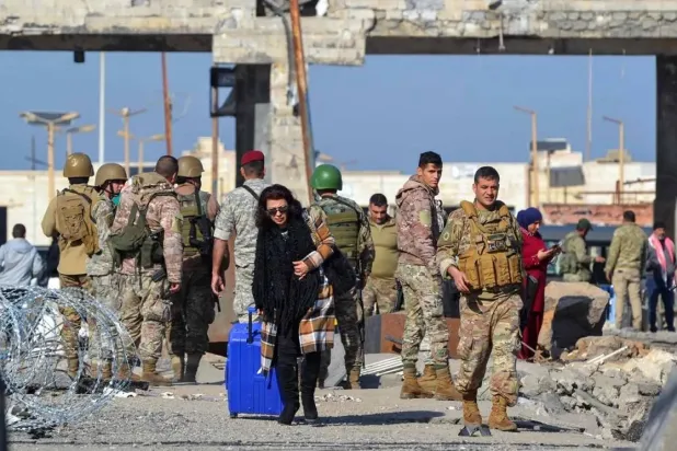 A woman arriving from Syria walks with her luggage into Lebanon through the northern crossing of Al-Arida on December 10, 2024. (AFP)