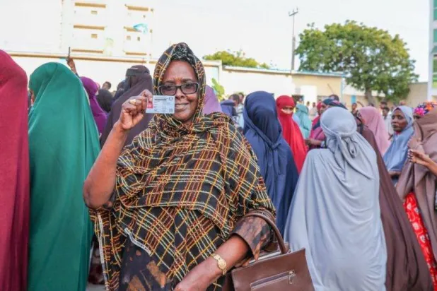 مواطنة صومالية ترفع بطاقتها الانتخابية خلال تجمع لدعم إجراء الانتخابات المحلية (وكالة الأنباء الصومالية)