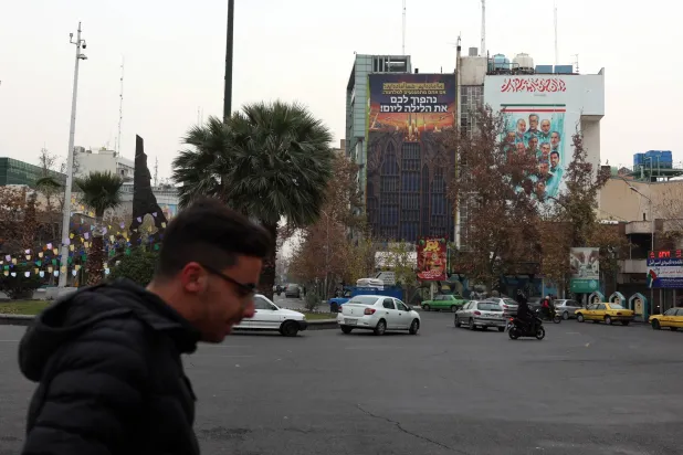 إيرانيون يمرون بجانب لوحة دعائية مناهِضة لإسرائيل تحمل عبارة باللغة الفارسية تقول: «نحن مستعدون. هل أنتم مستعدون؟» معلقة في ساحة فلسطين وسط طهران (إ.ب.أ)