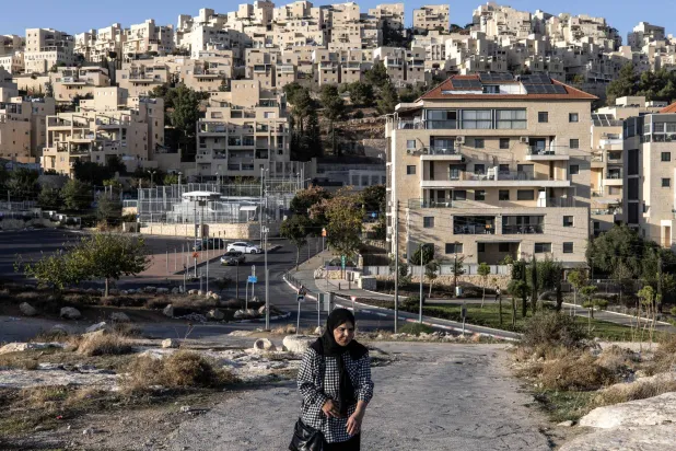 A Palestinian woman walks past the Israeli settlement of Har Homa, southeast of Jerusalem, on November 21, 2025. (AFP)