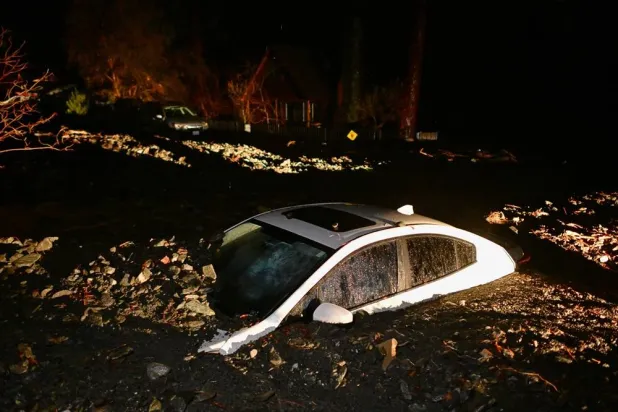  A car sits buried in mud after flooding Wednesday, Dec. 24, 2025, in Wrightwood, Calif. (AP) 