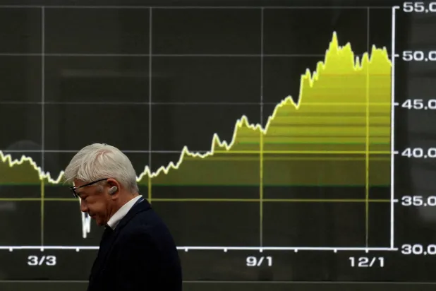 رجل يمر أمام لوحة إلكترونية تعرض مؤشرات حركة الأسهم وسط العاصمة اليابانية طوكيو (رويترز)