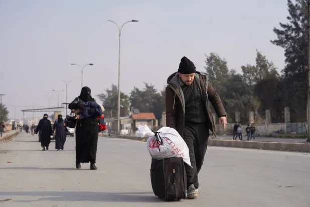 أشخاص مع أمتعتهم يسيرون على طول الطريق بعد أن اتفقت الحكومة السورية و«قوات سوريا الديمقراطية» على خفض التصعيد في مدينة حلب (رويترز)