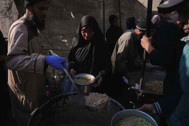  A Palestinian woman receives donated food at a community kitchen in Deir al-Balah, central Gaza Strip, Thursday, Dec. 25, 2025. (AP) 