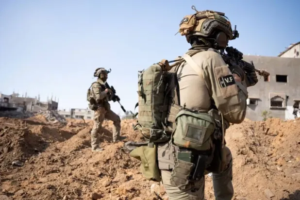 İsrail askerleri, Gazze Şeridi sınırına yakın güney İsrail'de konuşlanmış bir tank kulesinin tepesinde duruyor (AFP)